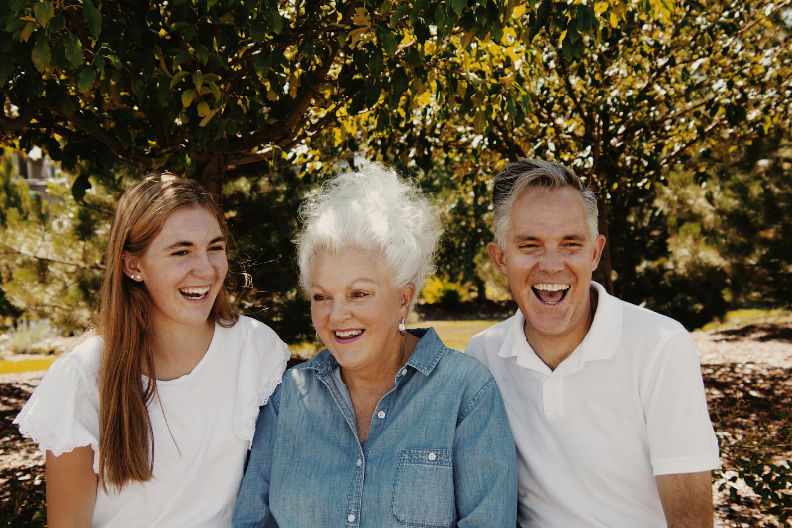 3 generations of a family laugh together outdoors.