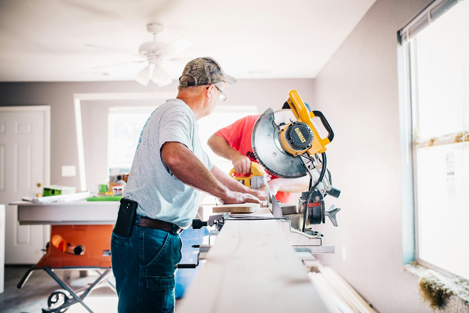 A contractor works with a miter saw inside a home under renovation.